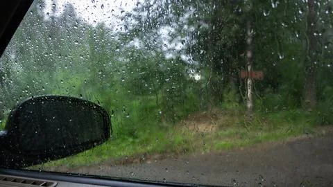 View from the car window in the rain through glass with water drops Stock Photos