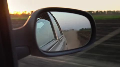 View from the car window into the rear view mirror. Sunset, steppe, Dirt road Stock Footage 210232771