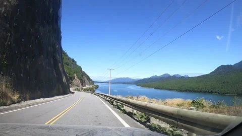 View from a car windscreen driving on a paved road along a river in Patagonia Stock Footage 130543412