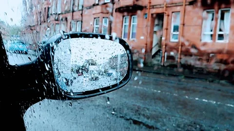 View of a cars side mirror through a rain soaked window Video stock 164059643