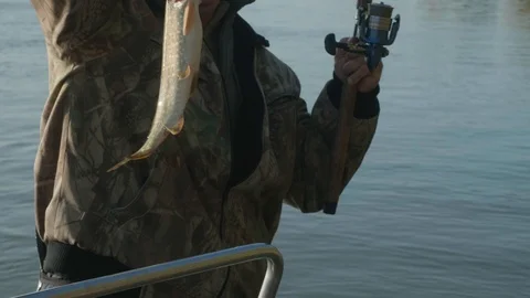 View of caught pike in man's hand. Fisherman is smiling being glad with his Video stock 124416427