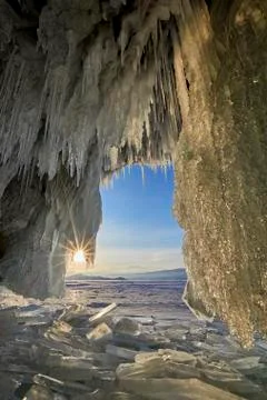 View from a cave covered with ice on the background of the sunset Stock Photos