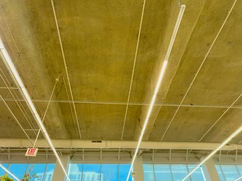 View of a ceiling with lights and a window in a building during daylight hour Stock Photos