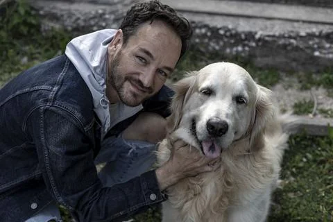 View of a cheerful guy playing with a beautiful dog on the stairs, view of a  Stock Photos