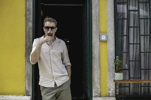 View of a cheerful guy working as bartender standing at the door of his cockt Foto stock