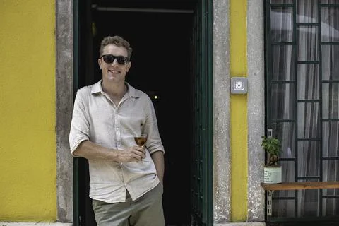 View of a cheerful guy working as bartender standing at the door of his cockt Foto stock