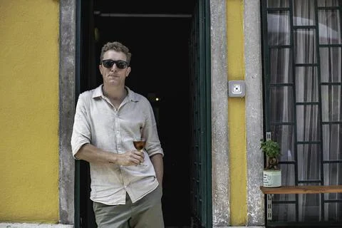 View of a cheerful guy working as bartender standing at the door of his cockt Stock Photos