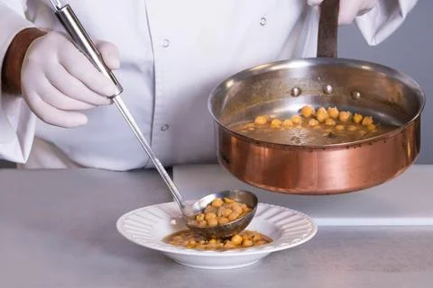 View of chickpea stew being served by a male chef using a ladle on an out of  Stock Photos