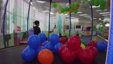 The view of a child walking on a trampoline filled with balloons and enclos.. Stock Footage 275315042