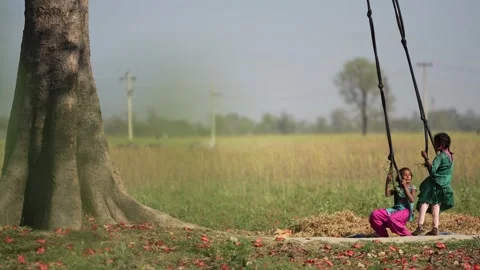 View of children playing on a swing under a large tree, Nepal. Video stock 335476880