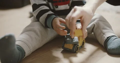 View of childs and mamas hands playing excavator on the wooden floor Stock Footage 154100711