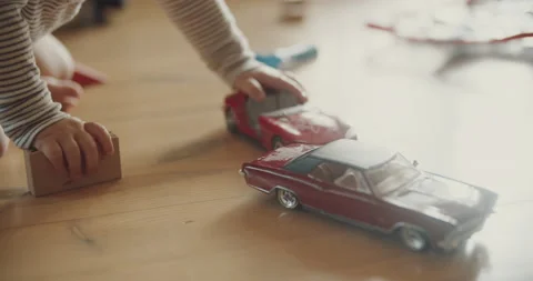 View of childs hands playing car models and wooden blocks on the floor Video stock 137042223