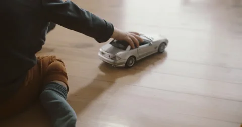 View of childs hands playing silver car model on the wooden floor Stock Footage 152986540