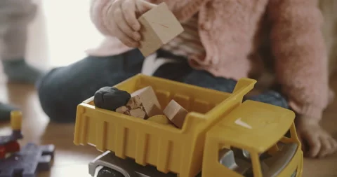 View of childs hands putting Construction Materials to a plastic yellow van Stock Footage 153237354