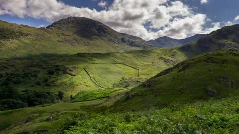 A view of a circular farm wall is light by summers sunshine in th Langdales, Stock Photos