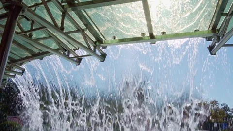 View of the city park through a waterfall from a glass roof. Slow Motion. Stock Footage 119129211