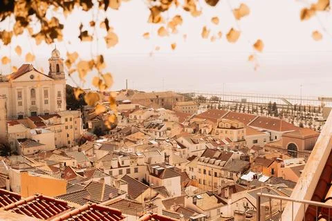 View of city rooftops in Lisbon during warm afternoon with church and sea in  Stock Photos