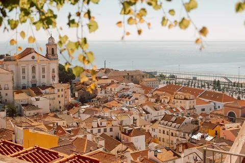 View of city rooftops in Lisbon during warm afternoon with church and sea in  Foto stock