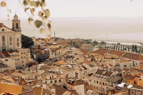 View of city rooftops in Lisbon during warm afternoon with church and sea in  Stock Photos