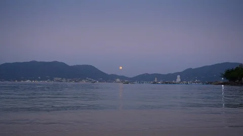 View on a city from sandy beach with small waves and calm sea with hills Stock Footage 114919953