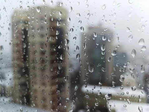 A view of a city through a window with rain drops on it Stock Photos
