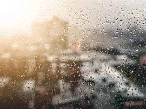 View of the city through the window on a rainy day with the sun on the right and Stock Photos