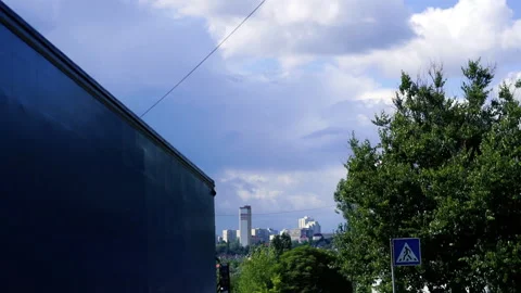 View of the cityscape through green trees anr heavy rainy clouds over the city Видео 204937420