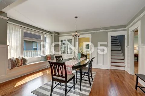 View of a classic dining room with gray walls and medium tone hardwood floors Stock Photos
