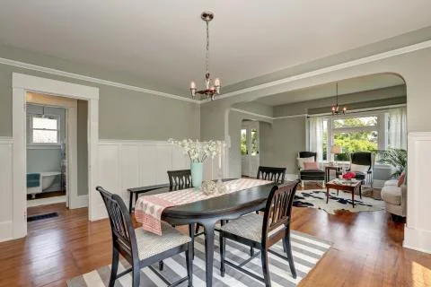 View of a classic dining room with gray walls and medium tone hardwood floors Stock Photos