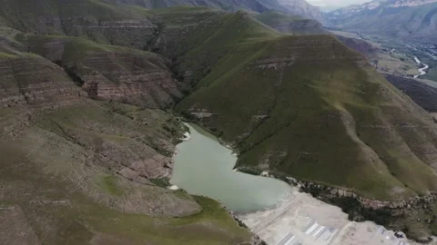 A view of clear mountain lake of irregular shape located between green hills Stock Footage 161072870