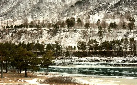 View of a clearing of ice in the bed of a beautiful turquoise river flowing t Stock Photos