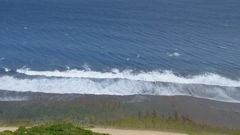 View from a cliff or hill on a beautiful beach with dark blue water Video stock 114991453