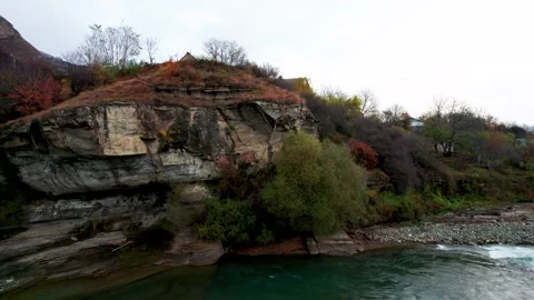 View of the cliff overhanging the mountain river and abandoned buildings on Stock Footage 170729786