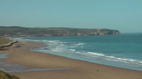 View from cliff top along almost deserted beach at low tide Stock Footage 2924144