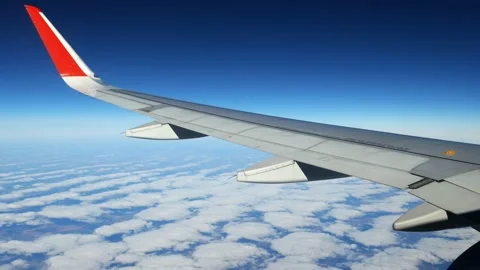 View of a cloud and an airplane wing through a porthole in a jet plane from the Stock Footage 166316886