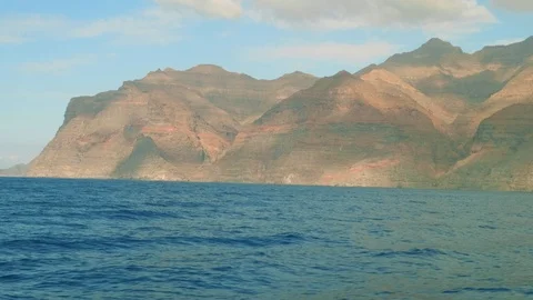 View of clouds above cliffy shore of Gran Canaria from board of yacht saling in Stock Footage 90005641