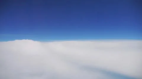 A view of clouds from above during a flight in a clear blue sky in 4K Stock Footage 286255769