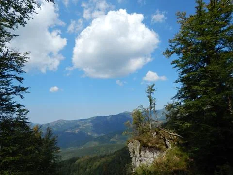 View of the clouds above the mountains framed by trees Stock Photos