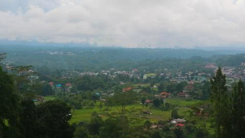 The view of the cloudy sky, trees, mountains and houses was photographed from Stock Photos
