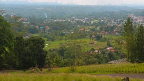 The view of the cloudy sky, trees, mountains and houses was photographed from Stock Photos