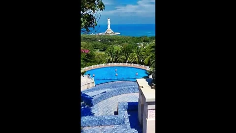 View of coastal statue and blue water pool from a hillside in a tropical locatio Stock Footage 327181723