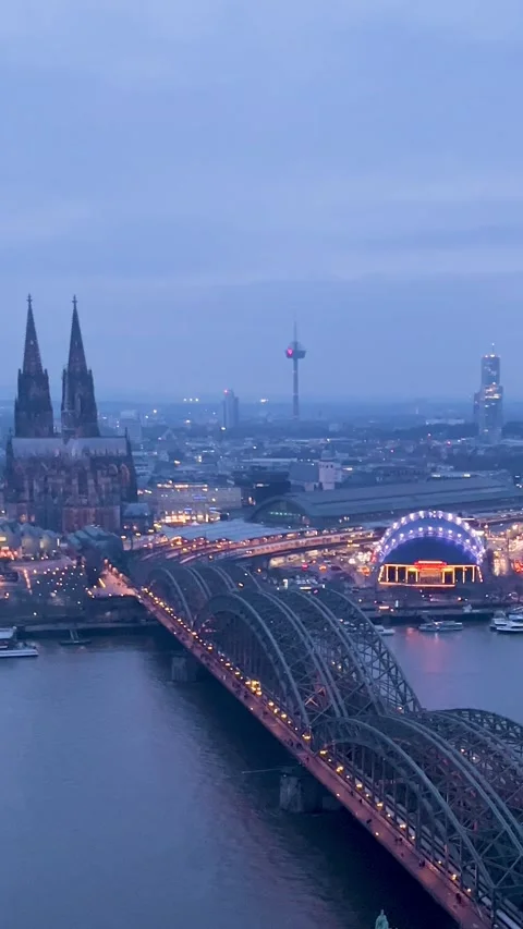 View of Cologne at Dusk With Lights on Bridge and Buildings by the River Stock Footage 329241966