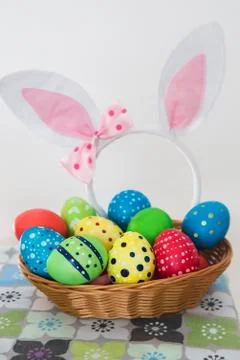 View of colorful Easter eggs in a basket standing on the table. Stock Photos