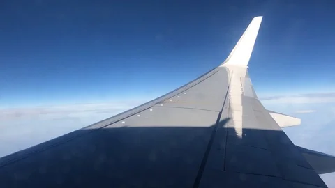 View of commercial plane wing over land and sea clouds and horizon blue sky Stock Footage 98635487