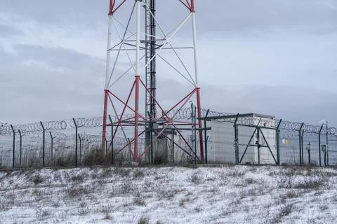 View of a communication tower surrounded by a security fence in a snowy lan.. Stock Photos