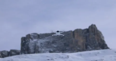 View of a Compact Drone Flying Near a Snowy Mountain Peak Stock Footage 346473096