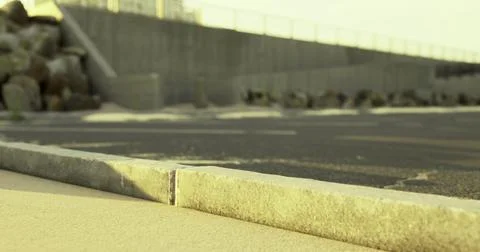 View of a concrete pathway by a coastal area at sunset with rocks and barrier Stock Illustration
