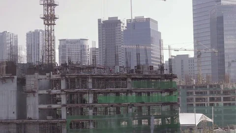 A view of a construction with workers on top and buildings on background 库存影片 79313335