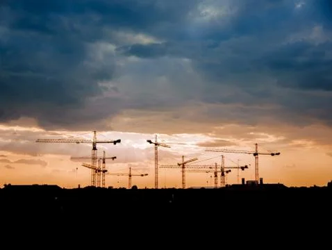 View on a consturction site with cranes during sunset Stock Photos