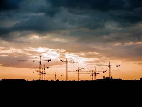 View on a consturction site with cranes during sunset Stock Photos